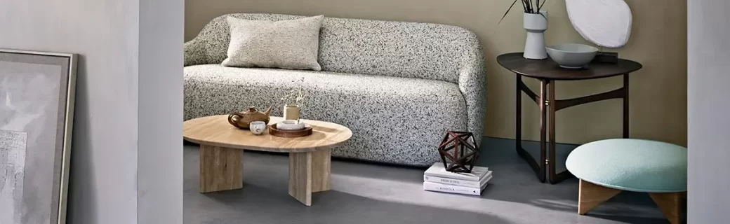 Stijlvolle zithoek met afgeronde bank, kunstobjecten en een donkere Novilon vloer met industriële uitstraling.