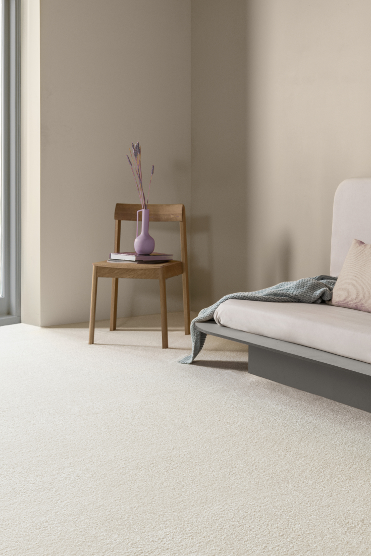 Minimalistisch interieur met licht hoogpolig tapijt, houten stoel en zachte pasteltinten in de styling
