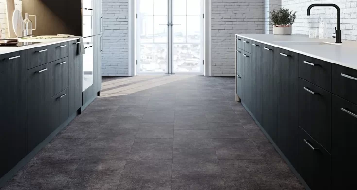 Donkere tegelvloer in moderne keuken met zwarte keukenkasten en wit werkblad, verlicht door natuurlijk daglicht