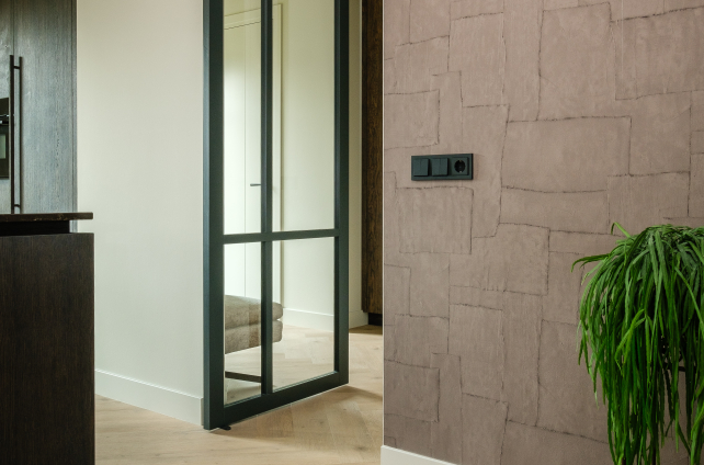 Natuurlijke eiken visgraatvloer in modern interieur met glazen deur en textuurwand