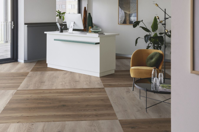 Moderne kantoorruimte met houtlook pvc vloer in visgraatmotief en stijlvolle zithoek met okergele fauteuil