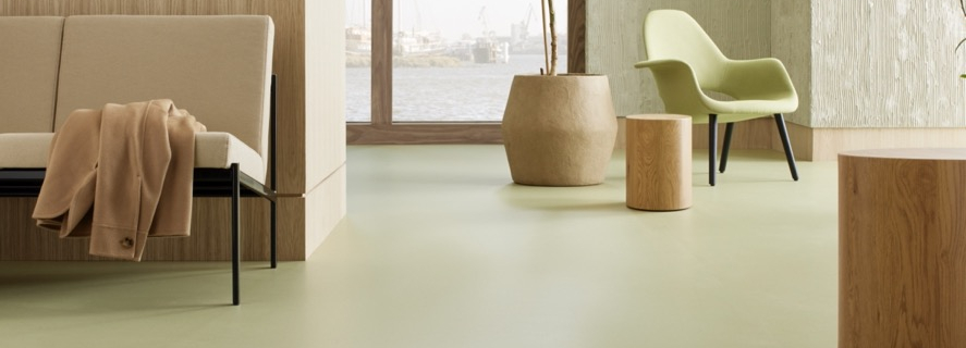 Groenbruine marmoleumvloer met natuurlijke uitstraling en houten kruk in minimalistisch interieur