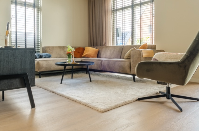 Laminaatvloer in een gezellige woonkamer waar een wit kleed op ligt