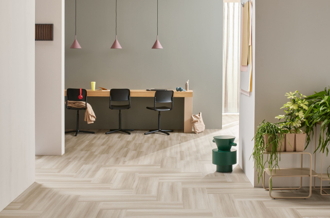 Lichte visgraat vinylvloer in moderne werkruimte met houten bureau en groene accenten