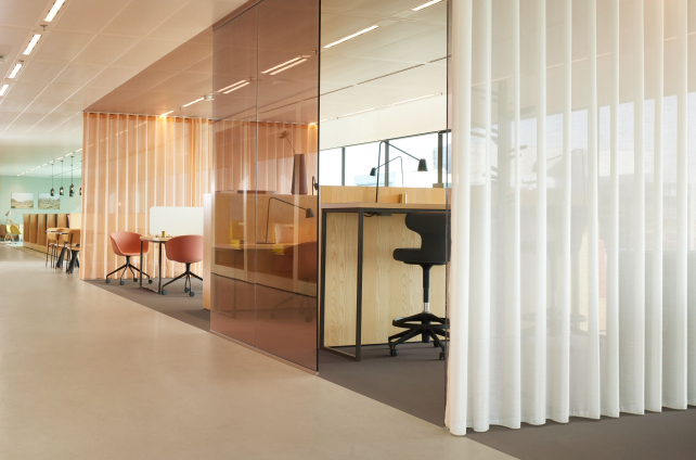 Moderne kantoorruimte met lichtgrijze marmoleumvloer, glazen wanden en flexwerkplekken in hout en pastelkleuren