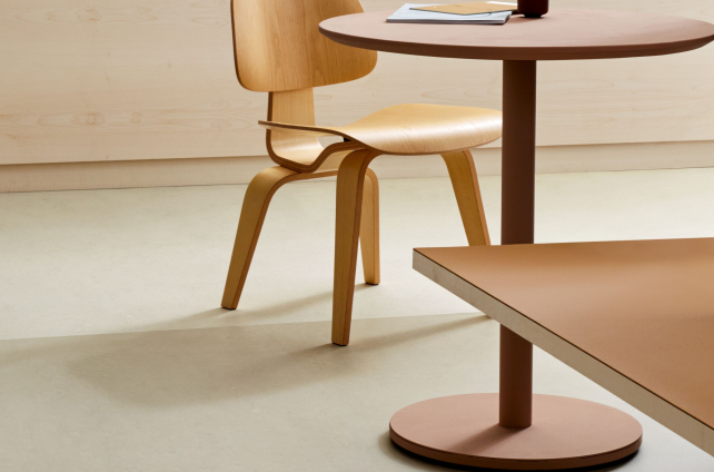 Natuurlijke marmoleumvloer met ronde eettafel en houten designstoel in een minimalistisch interieur