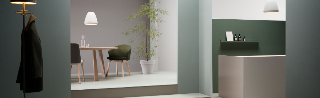 Minimalistisch interieur met zachte groentinten, lichtgrijze marmoleumvloer en houten meubels in een rustige setting