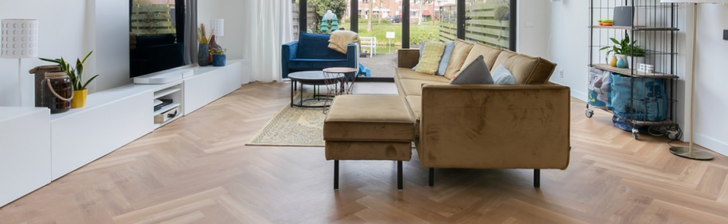 Licht visgraat pvc vloer in moderne woonkamer met okergele bank en grote raampartijen