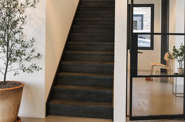 Trap bekleed met donkere pvc in moderne hal met glazen deur en natuurlijke styling