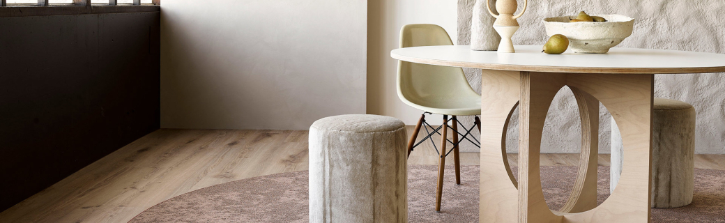 Luxe eikenhouten vloer met modern rond vloerkleed en designmeubels in warme, natuurlijke tinten