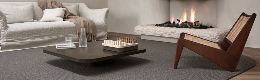Donkergrijs rond vloerkleed van Parade in een warme woonkamer met haard en natuurlijke tinten.