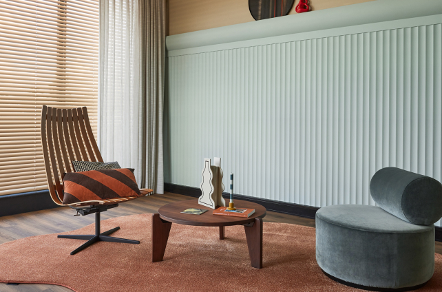 Organisch gevormd terracotta vloerkleed van Parade onder designfauteuils in een retro interieur.