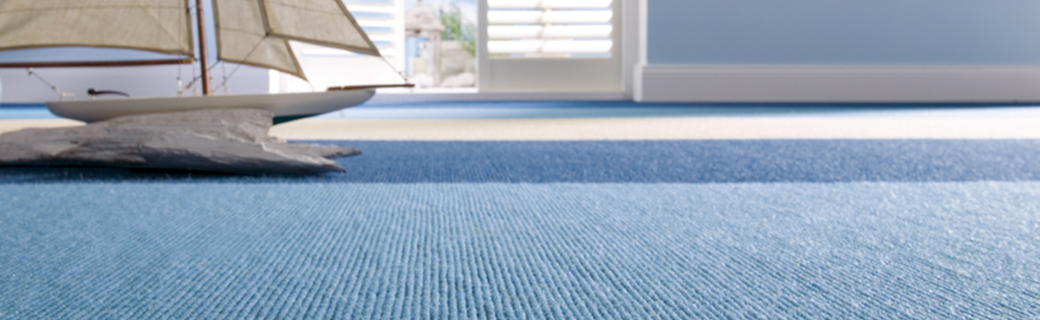 Licht interieur met blauw gestreept tapijt en decoratief zeilbootmodel bij openslaande deuren