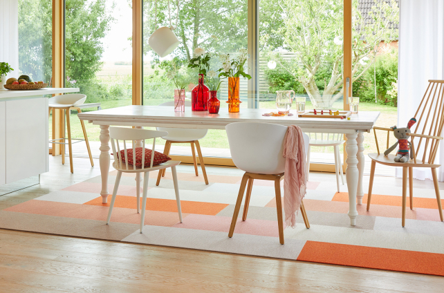 Lichte eetkamer met houten vloer, wit eiken eettafel en kleurrijk vloerkleed in oranje en roze tinten