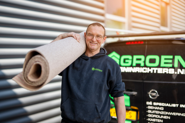 werknemer heeft een rol vloerbedekking die buiten staat bij het groeninrichters busje