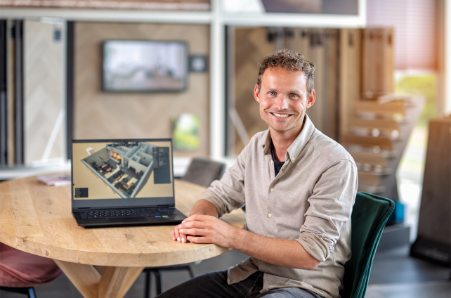 Interieurontwerper in showroom toont 3D-plattegrond op laptop tijdens adviesgesprek
