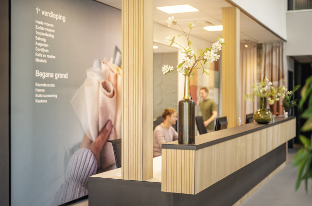 Bord met showroomindeling en houten ontvangstbalie met bloemenvaas