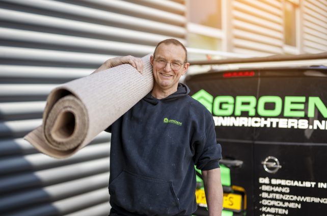 Medewerker van Deventer Vloeren met opgerolde vloerbedekking voor de bus